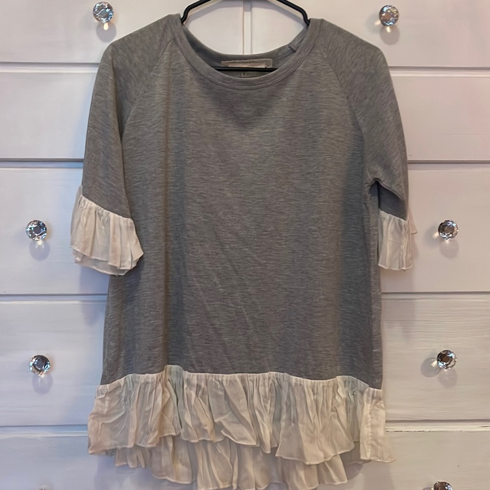 grey shirt with cream ruffles on the sleeves and bottom